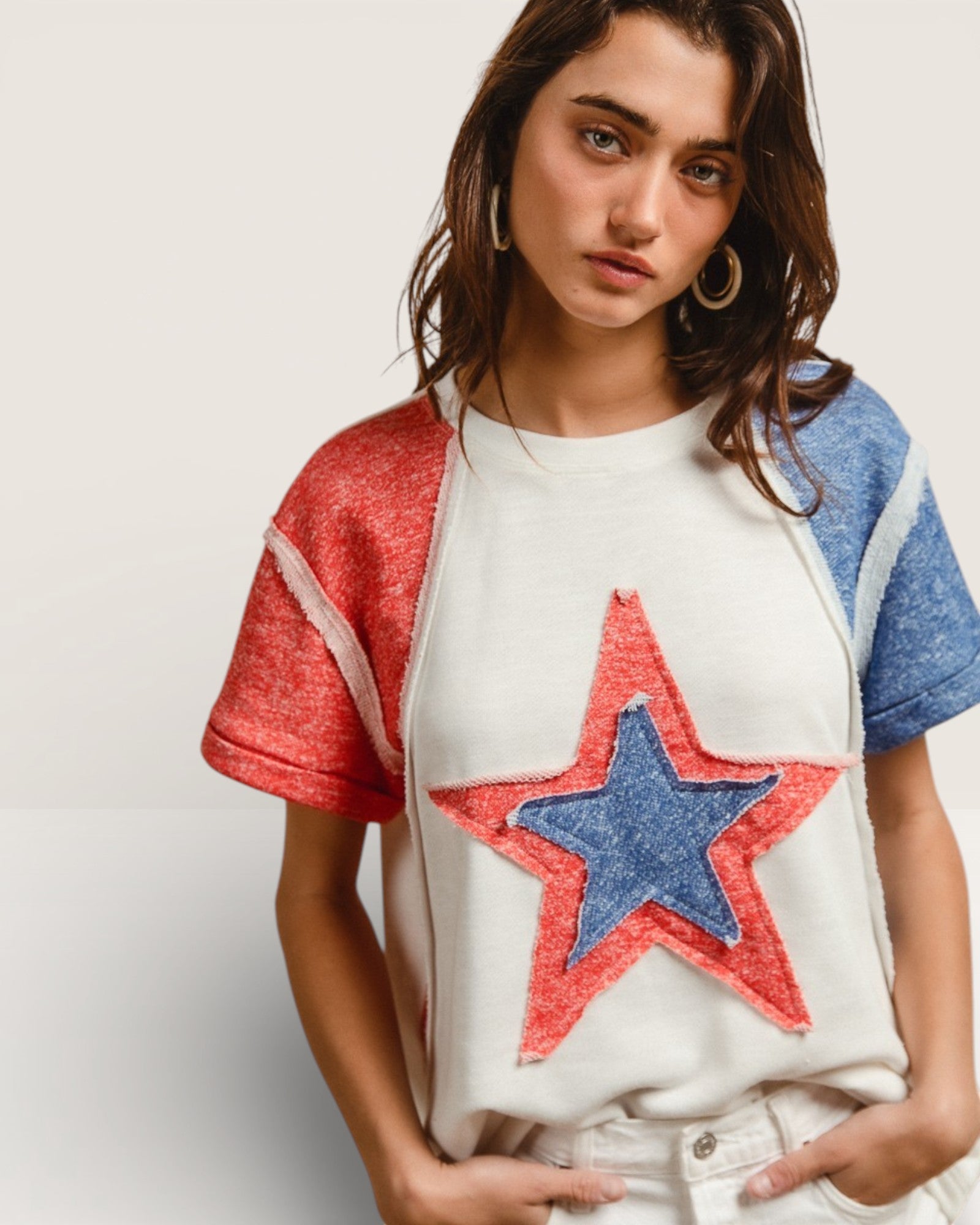 Woman wearing a white t-shirt with a red and blue star design on a plain background
