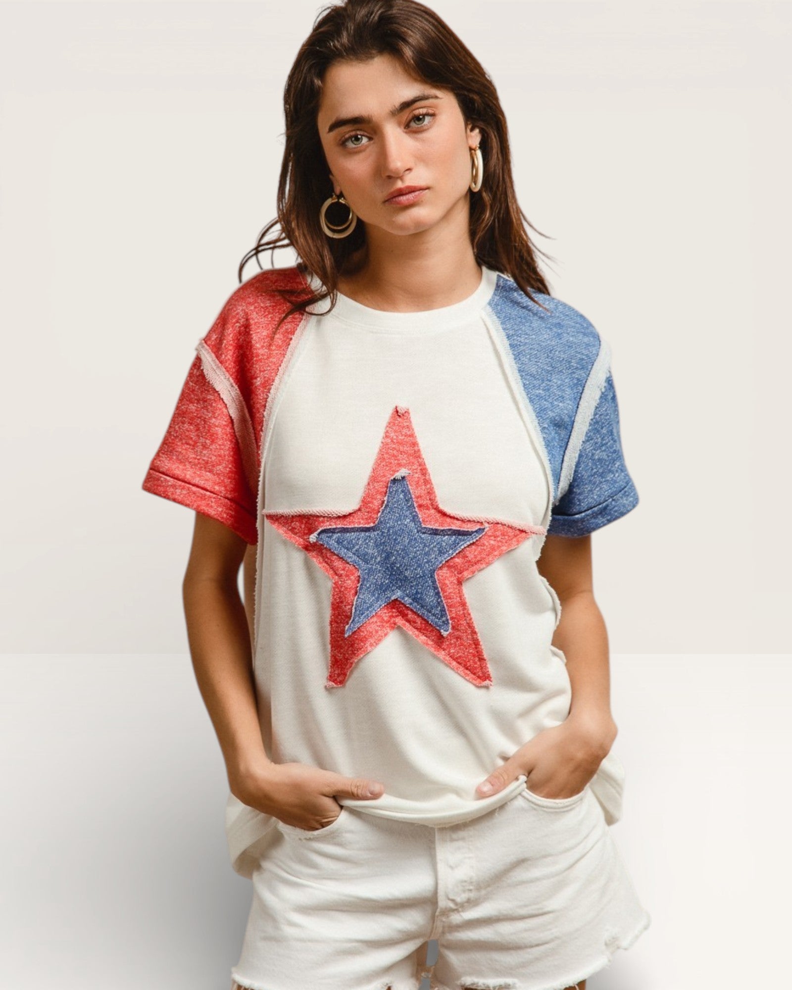 Woman wearing a white t-shirt with a red and blue star design on a plain background