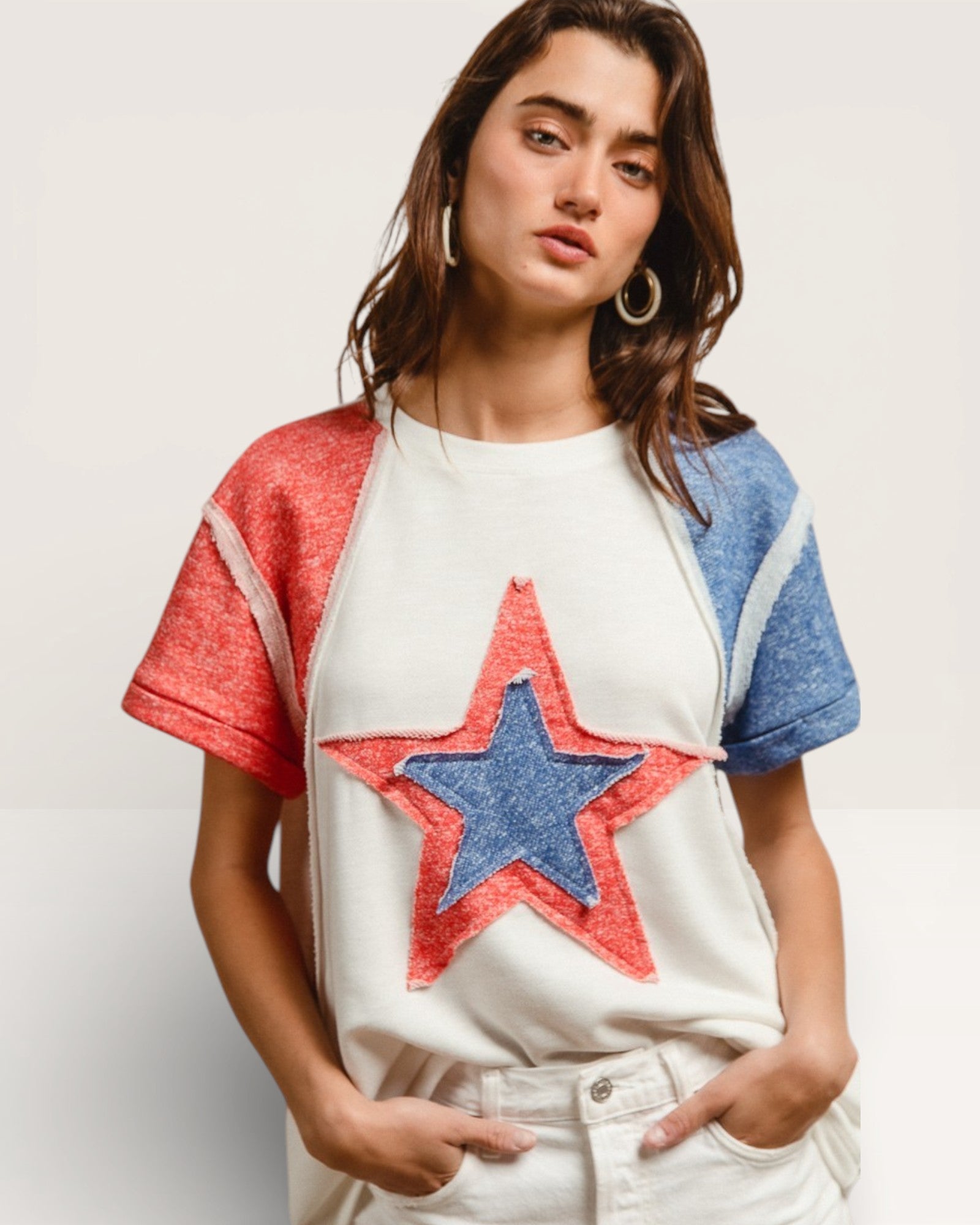 Woman wearing a white t-shirt with a red and blue star design on a plain background