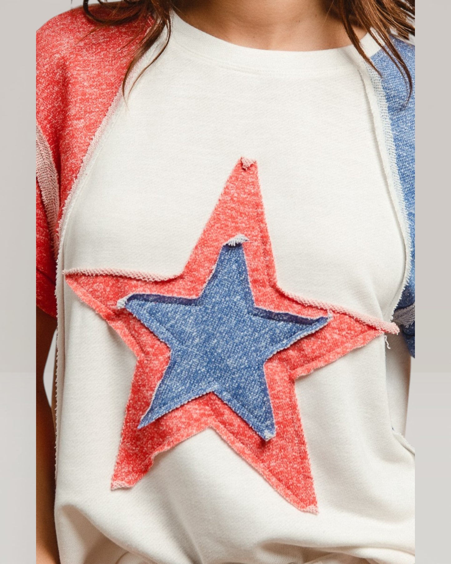 White sweater with a red and blue star patch worn by a person