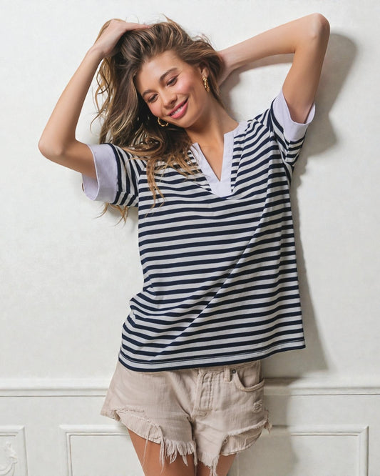 Woman wearing a striped shirt and shorts against a white wall