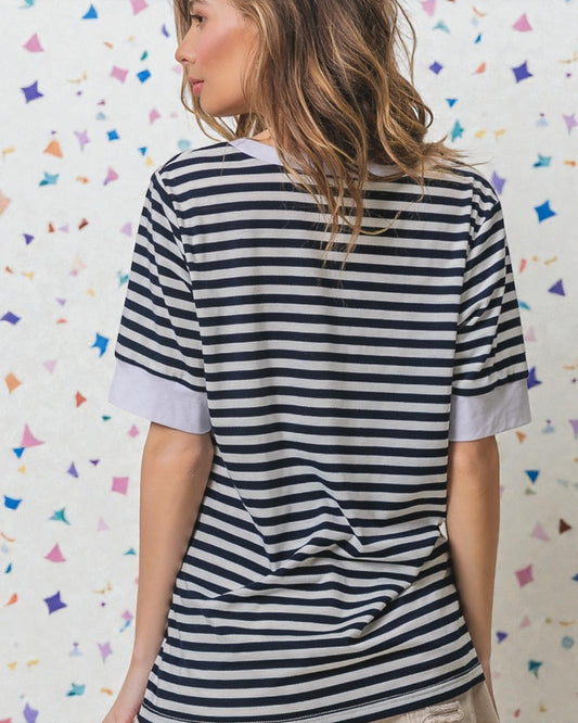 Woman wearing a black and white striped shirt against a colorful geometric patterned wall.