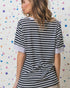 Woman wearing a black and white striped shirt against a colorful geometric patterned wall.