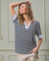 Woman wearing a black and white striped shirt against a neutral wall.