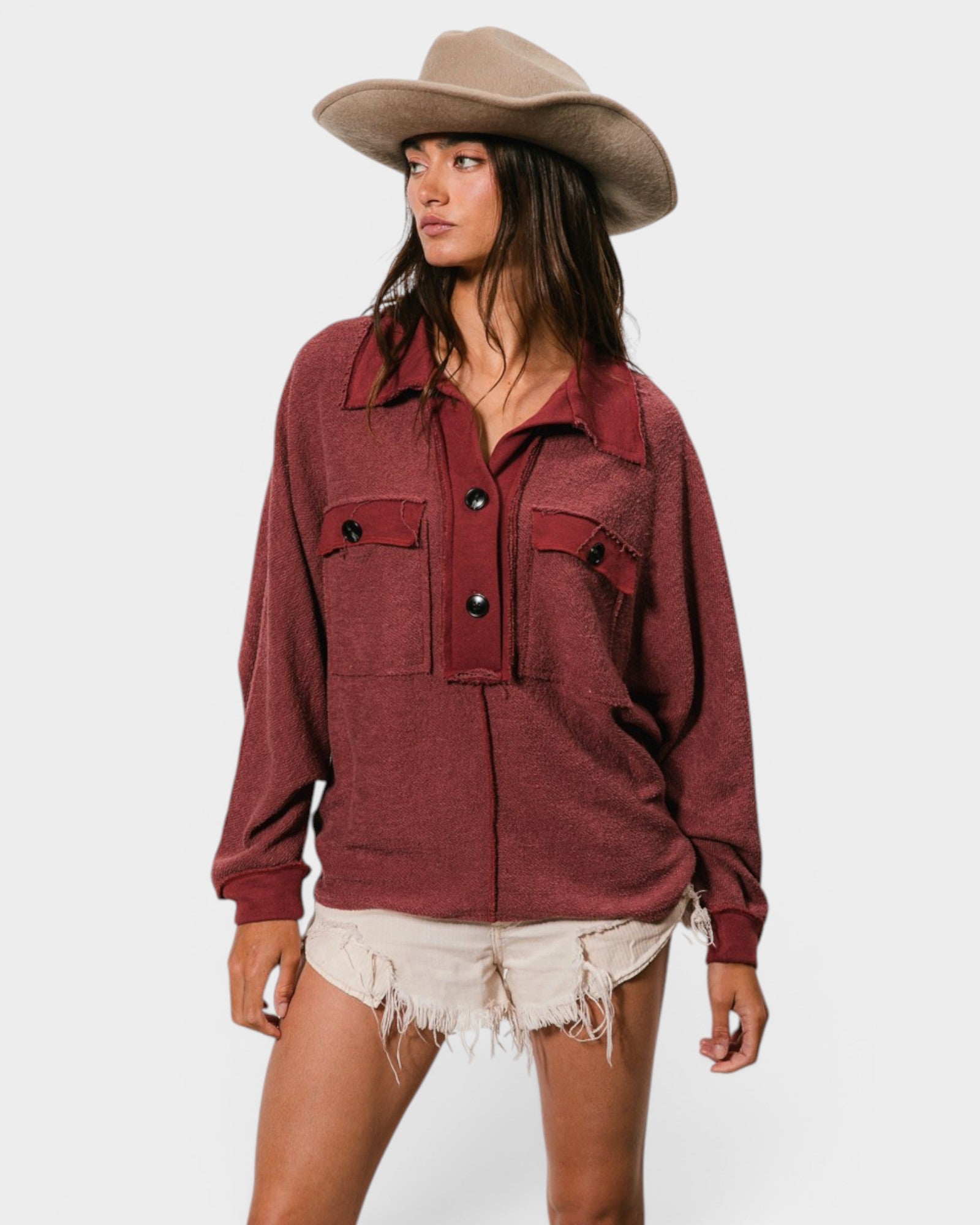 Woman wearing a burgundy top and beige hat on a white background