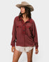 Woman wearing a burgundy top and beige hat on a white background