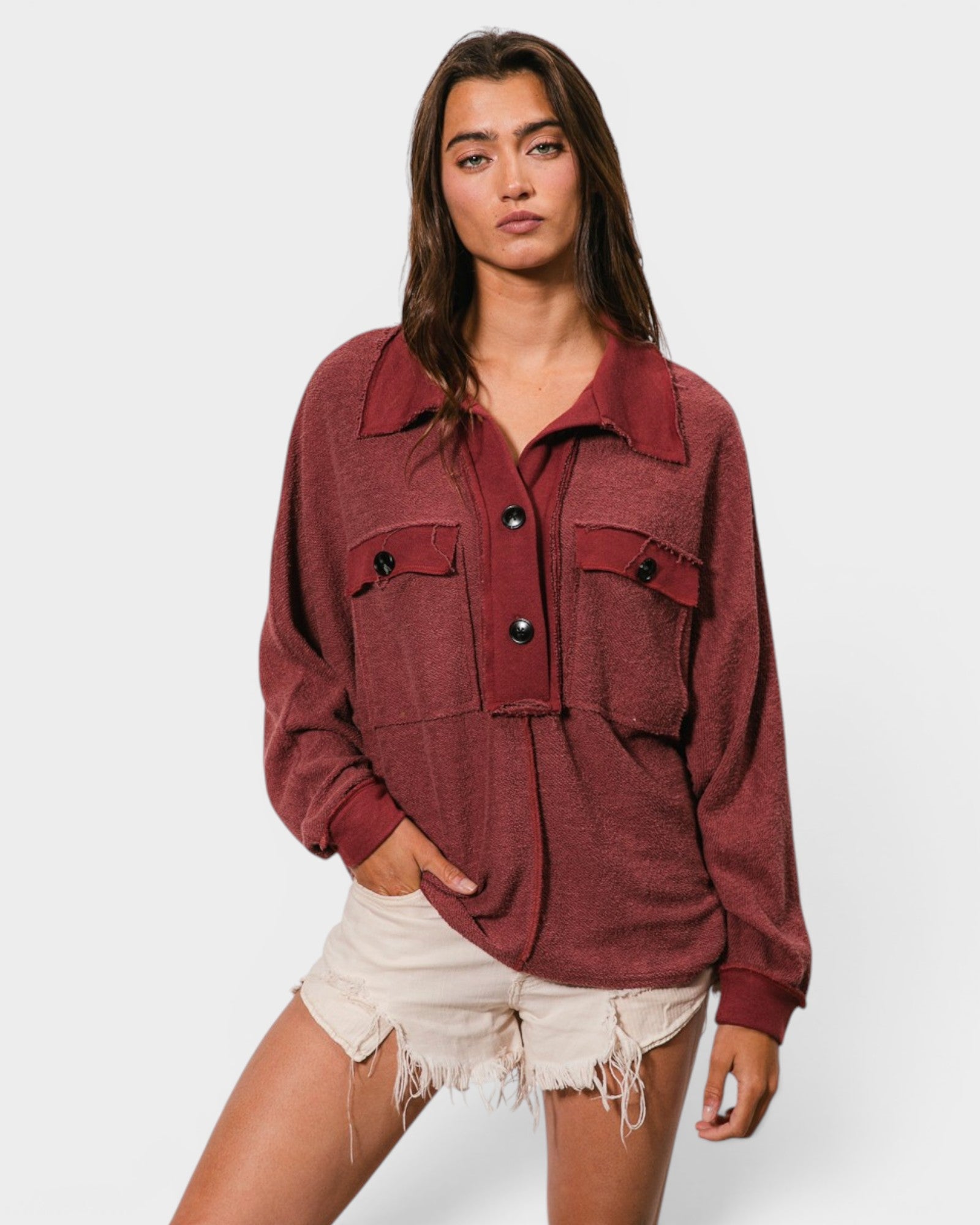 Woman wearing a red jacket and white shorts on a plain background