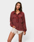 Woman wearing a burgundy top and white shorts on a plain background