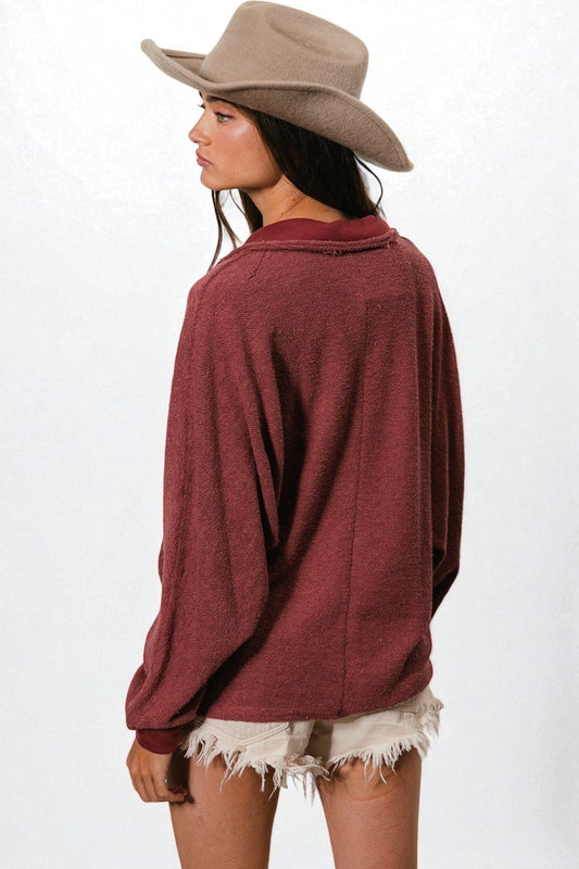 Woman wearing a burgundy top and beige hat on a white background