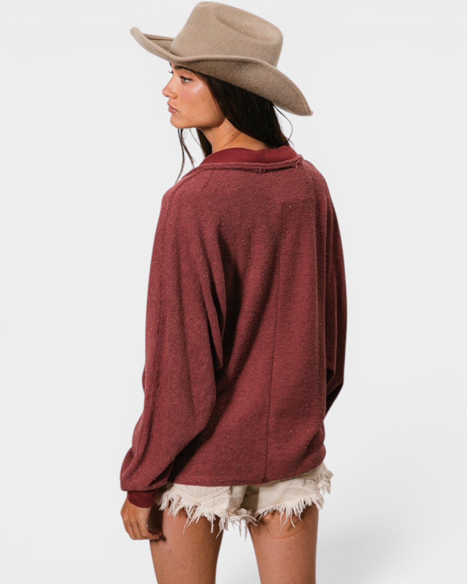 Woman wearing a burgundy sweater and beige cowboy hat on a white background