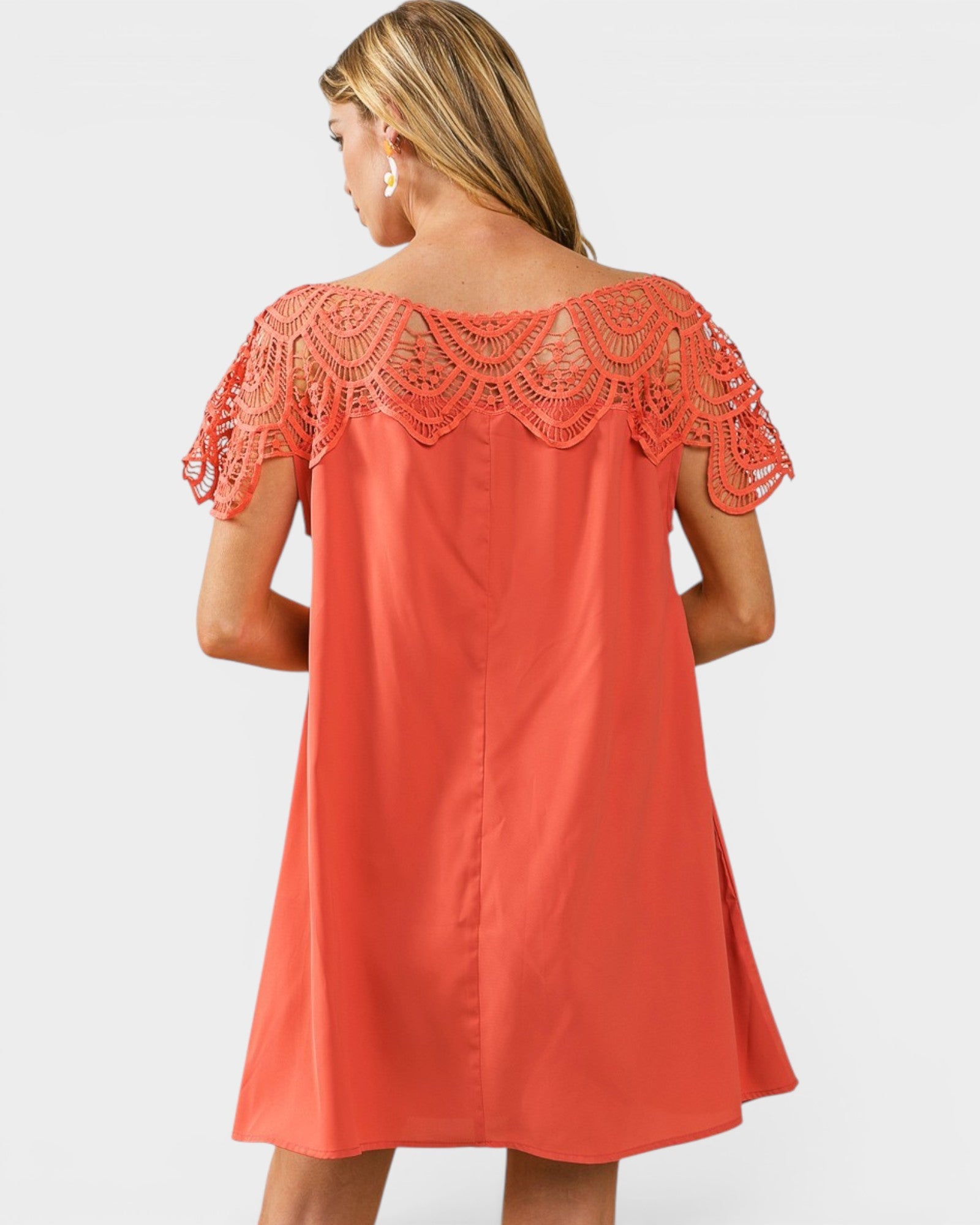 Coral dress with lace detailing on a plain background