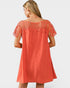 Coral dress with lace detailing on a plain background