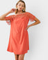 Woman wearing a coral dress with lace sleeves on a white background