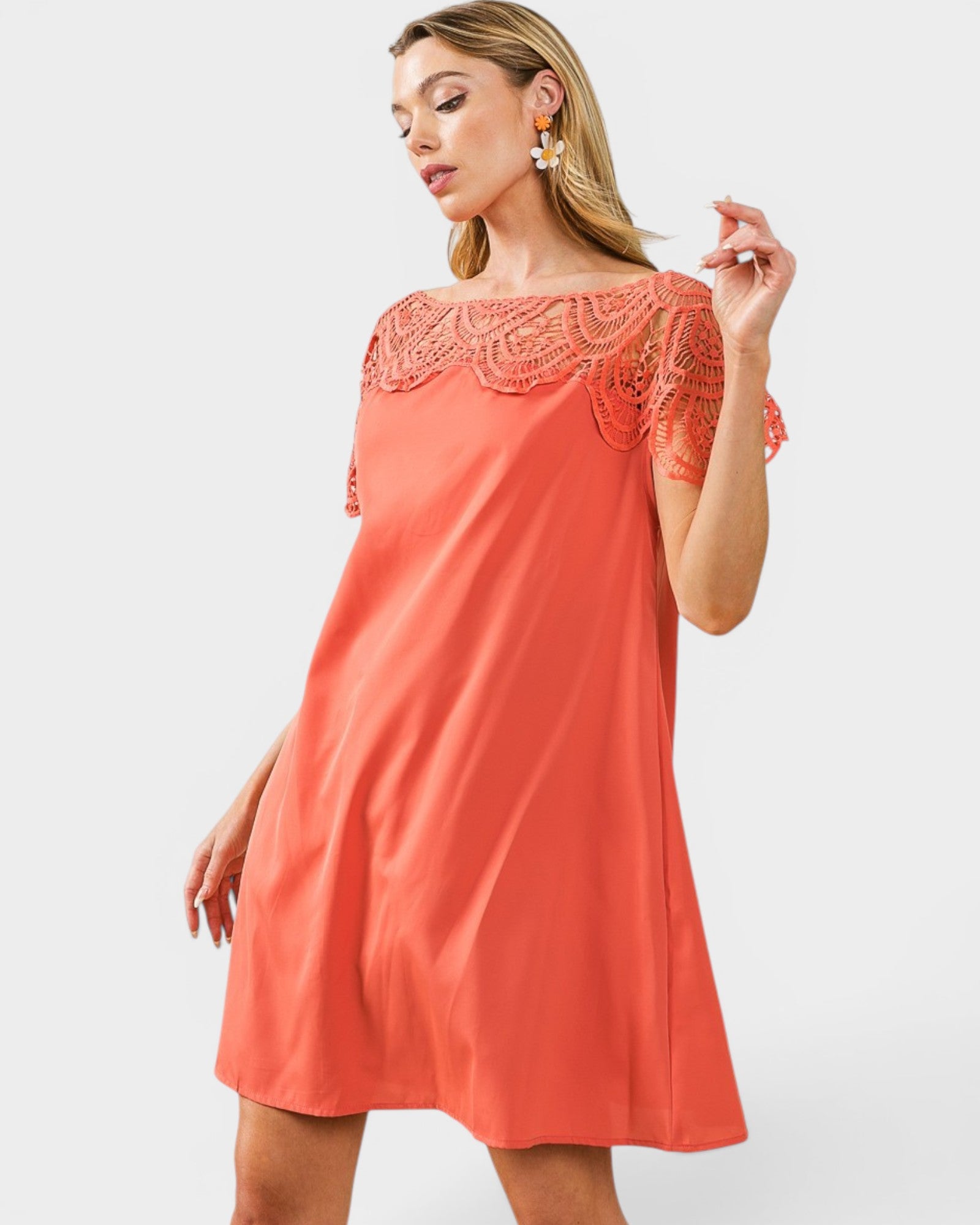 Woman wearing a coral dress with lace details on a white background