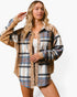 A woman modeling a long-sleeve plaid button-up shirt with leopard-print trim and sequined details, worn open over a white tank top against a plain light gray studio background.