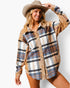 A woman wearing a long-sleeve plaid button-up shirt with leopard-print shoulder and side panels, paired with a brown cowboy hat, against a plain white studio background.