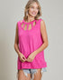 Woman wearing a bright pink sleeveless top with cut-out details on a plain background