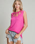Woman wearing a bright pink sleeveless top with cut-out details and denim shorts on a plain background
