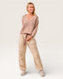 Woman wearing a beige ribbed sweater and pants on a white background