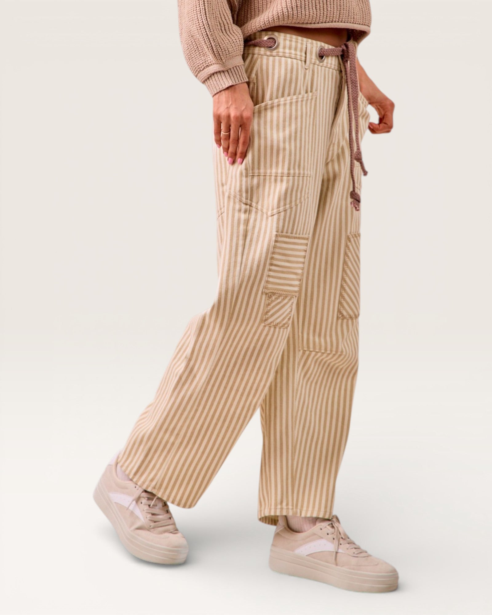 Person wearing beige striped pants and matching shoes on a white background