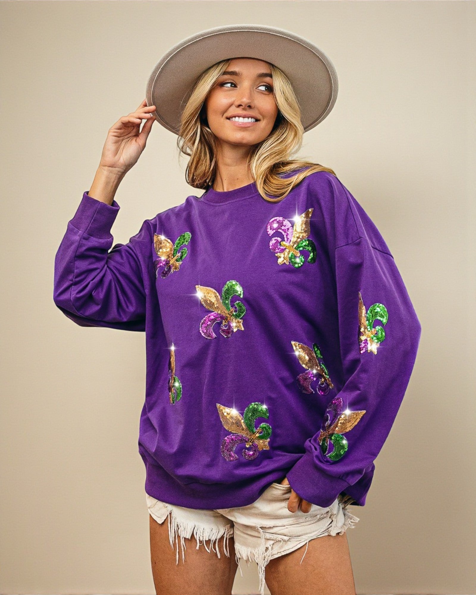Woman wearing a purple sweatshirt with colorful designs on a beige background