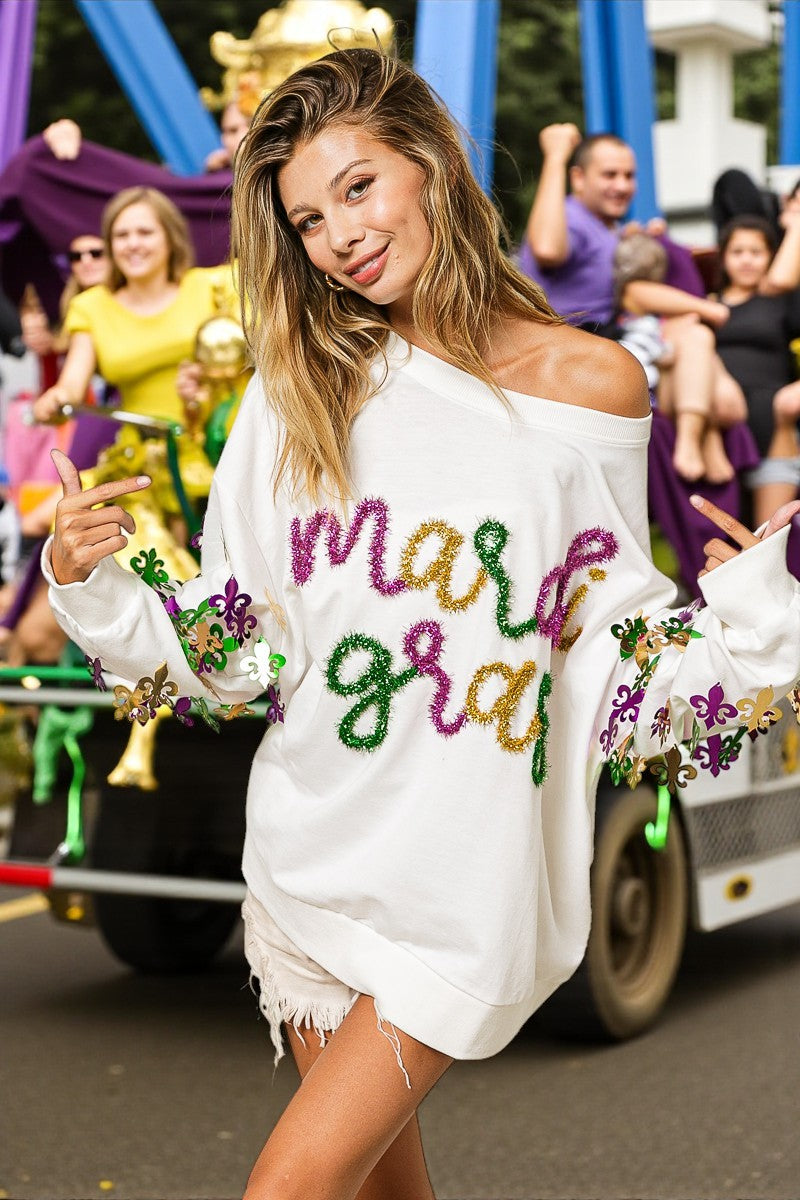 Woman wearing a white off-shoulder top with colorful text and decorations, standing in front of a parade float.