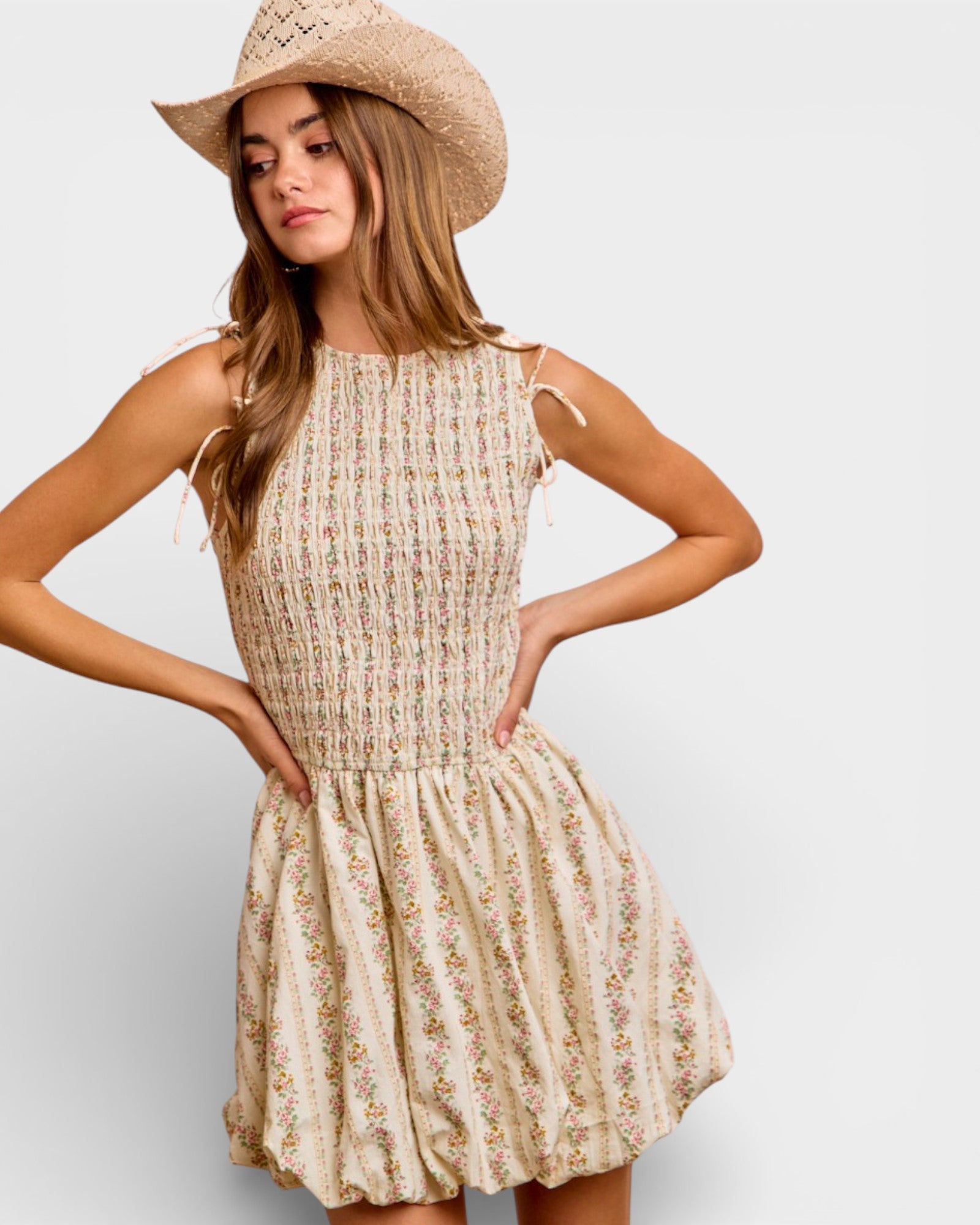 Woman wearing a floral dress and straw hat on a plain background