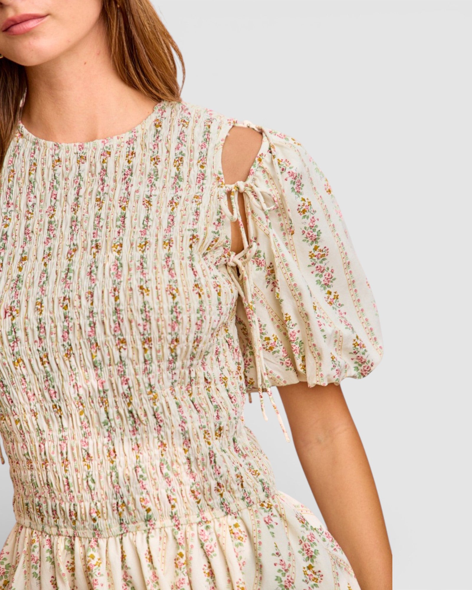 Woman wearing a floral dress with puff sleeves on a plain background