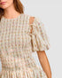 Woman wearing a floral dress with puff sleeves on a plain background