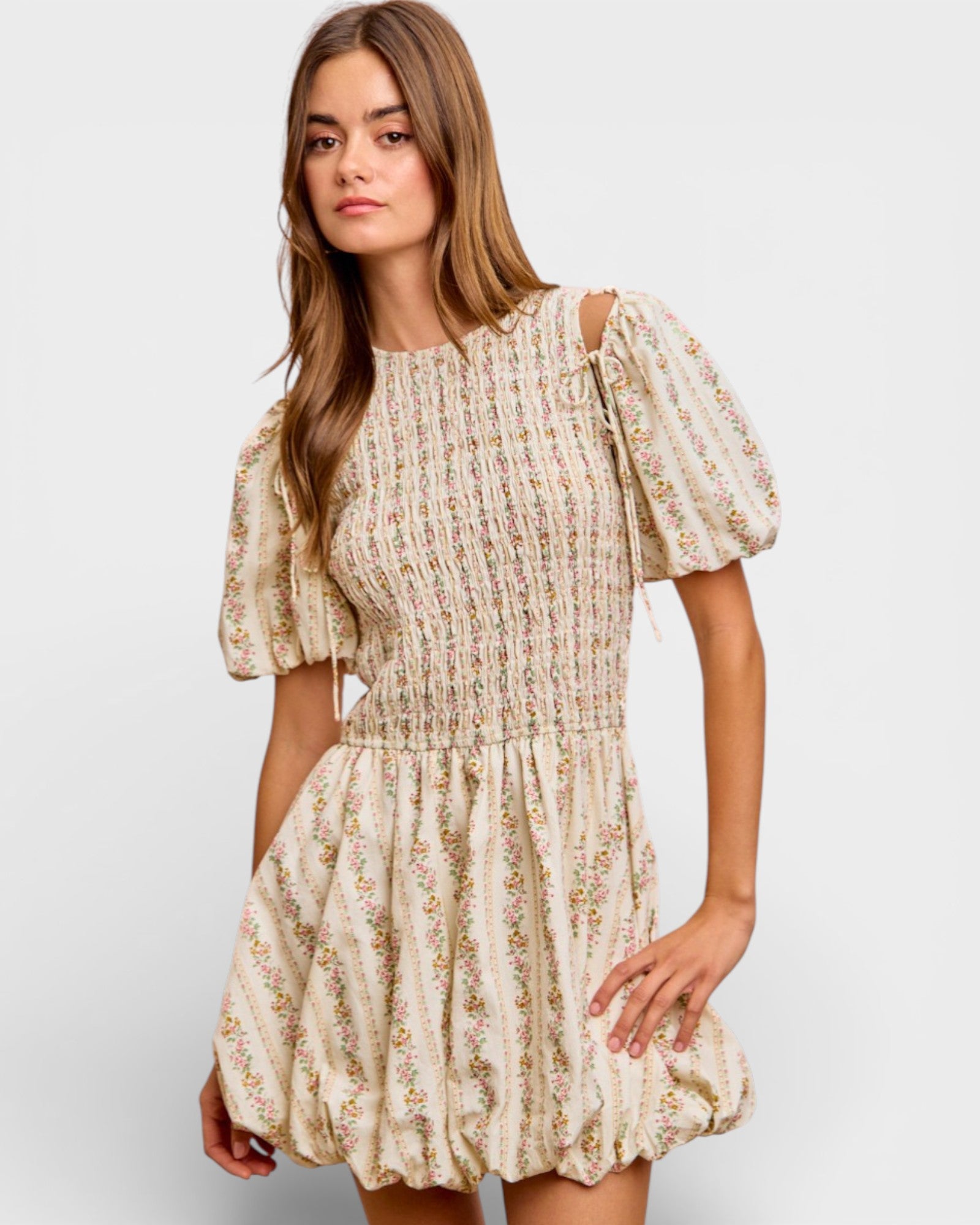 Woman wearing a floral dress with puff sleeves on a plain background