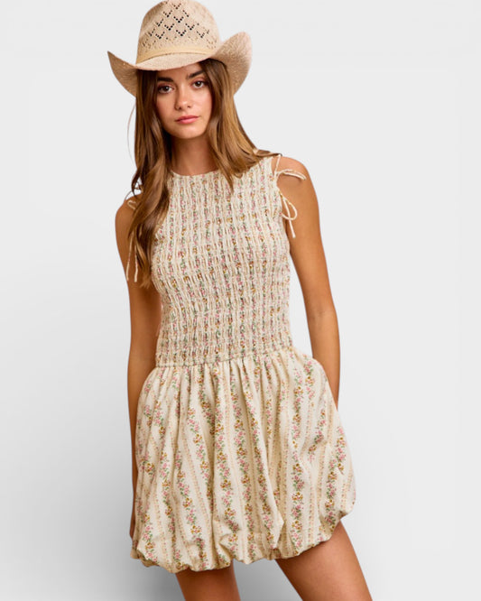 Woman wearing a floral dress and straw hat on a plain background