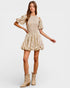 Woman wearing a patterned dress and beige boots on a white background