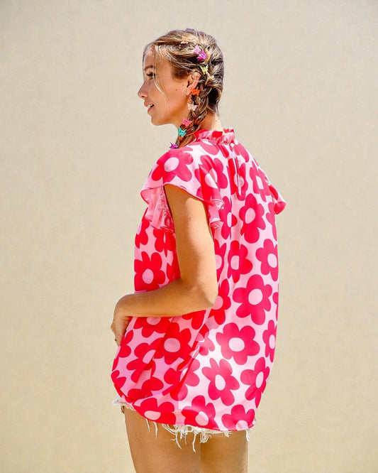 Woman wearing a red and pink floral cover-up against a beige background