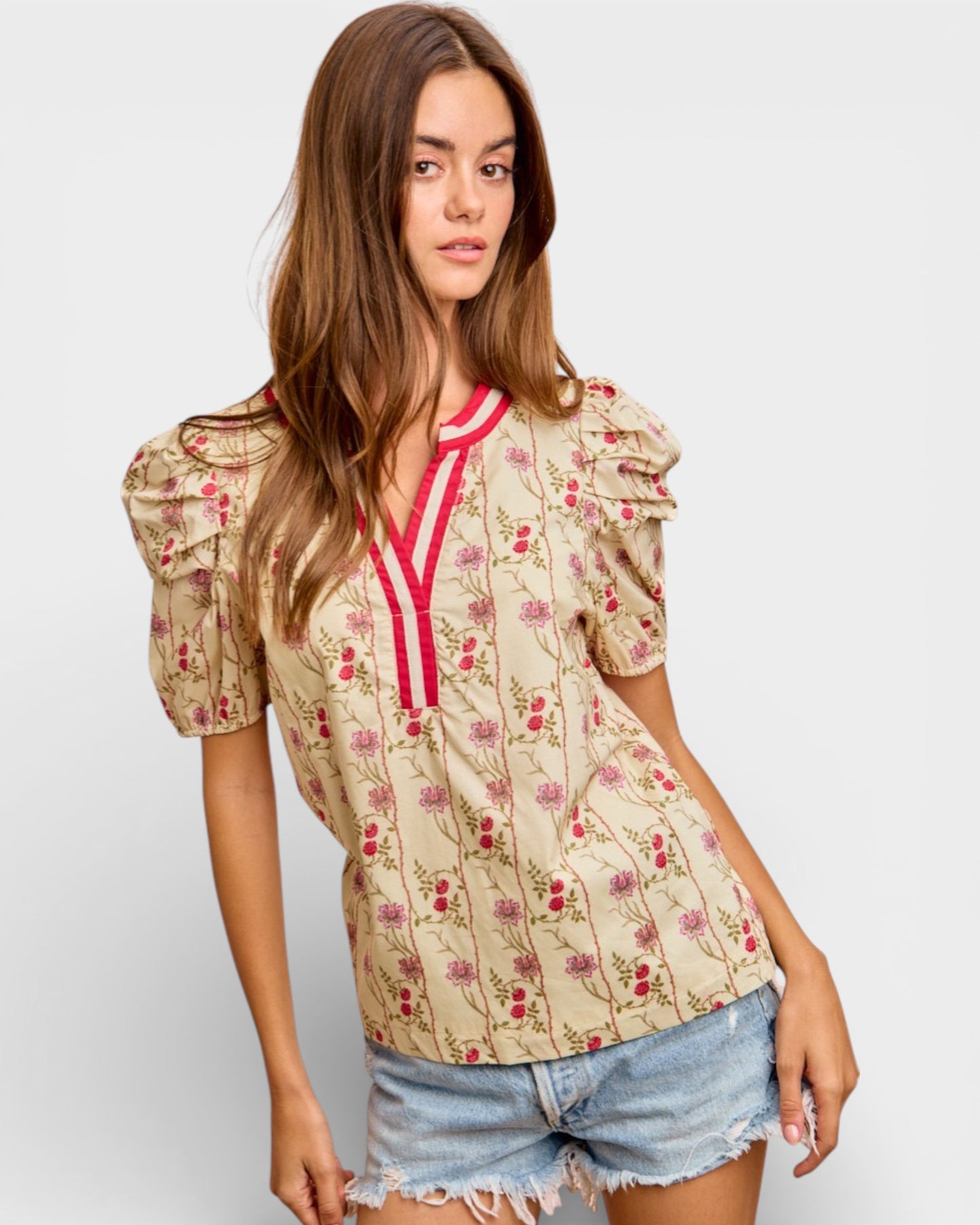 Woman wearing a floral blouse with puffed sleeves on a plain background