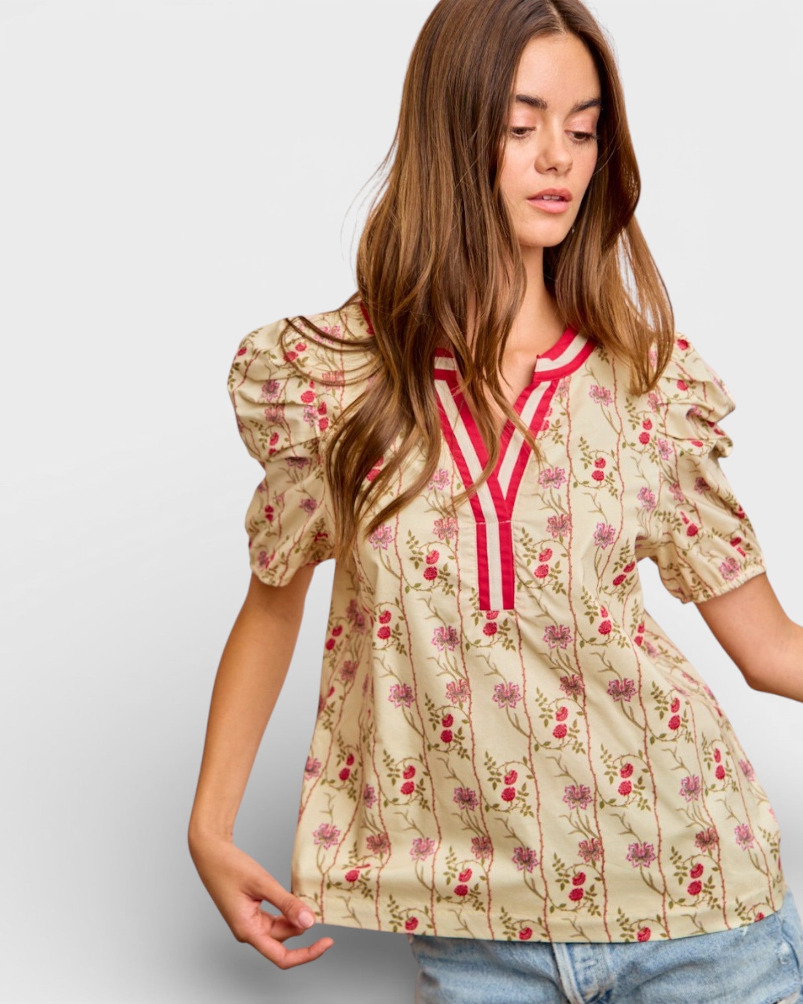 Woman wearing a floral blouse with puff sleeves on a plain background