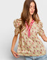 Woman wearing a floral blouse with puff sleeves on a plain background