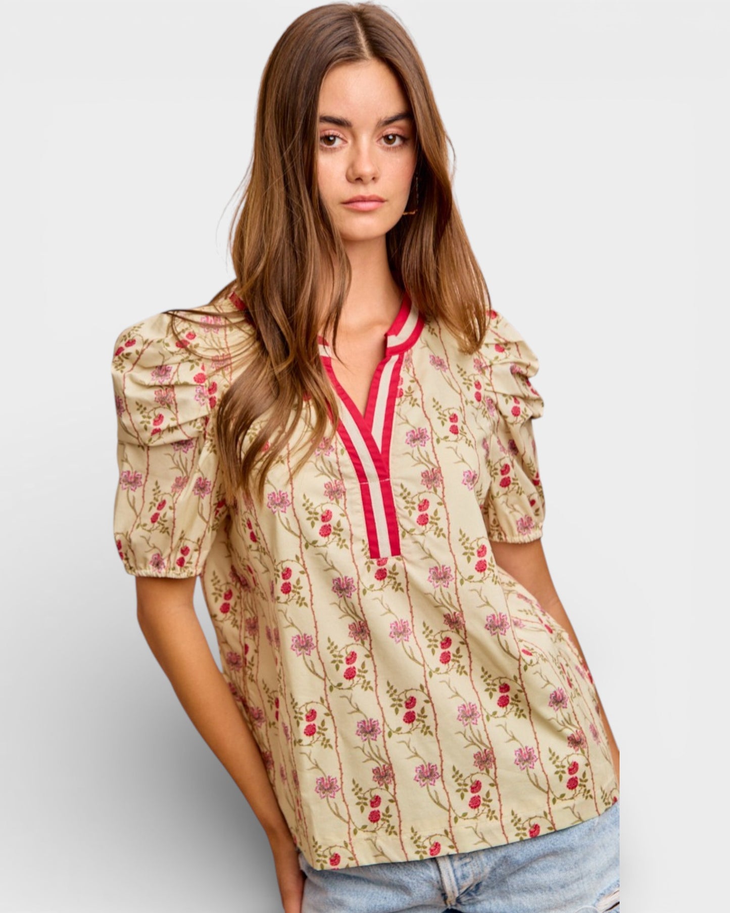 Woman wearing a floral blouse with puff sleeves on a plain background