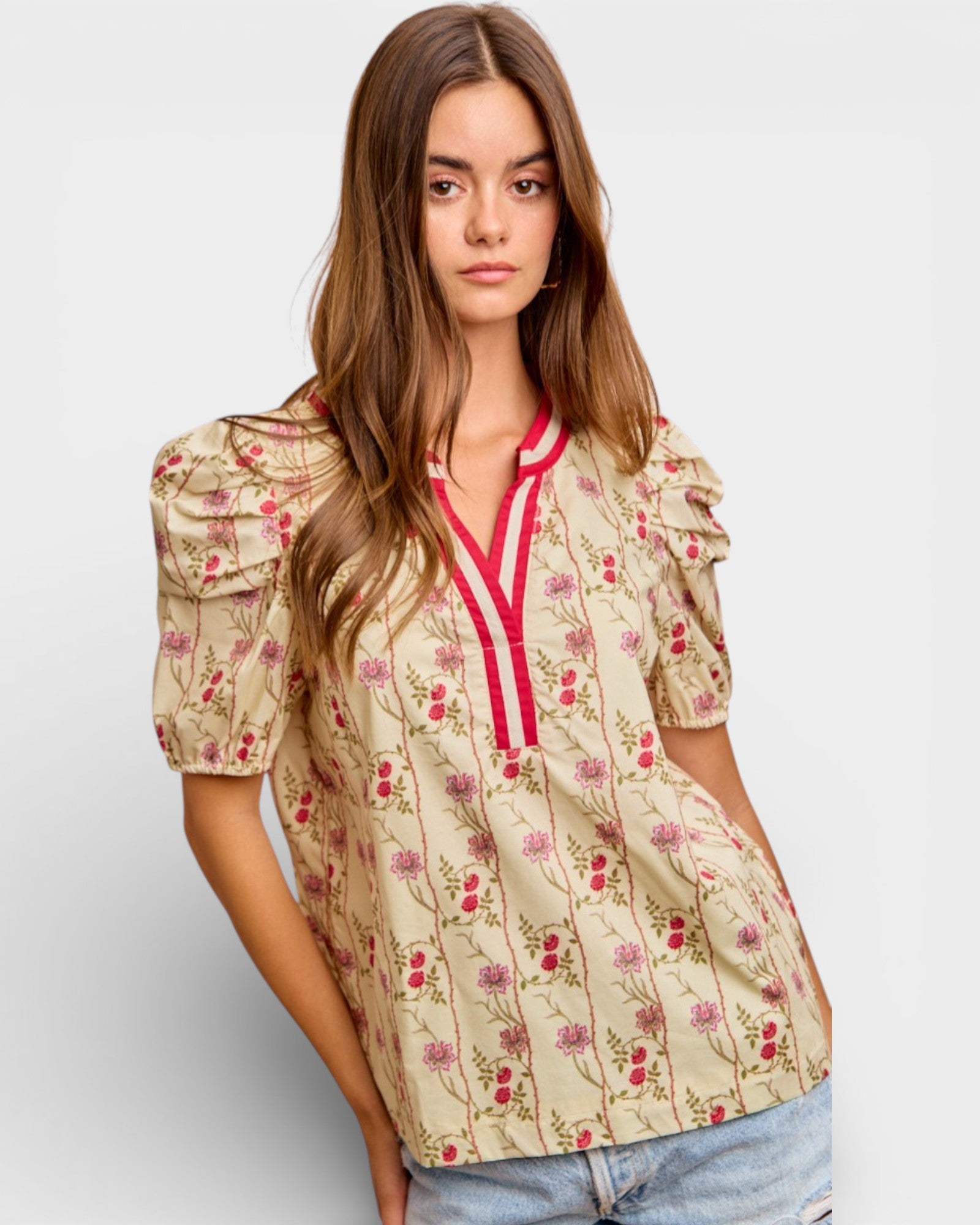 Woman wearing a floral blouse with puff sleeves on a plain background