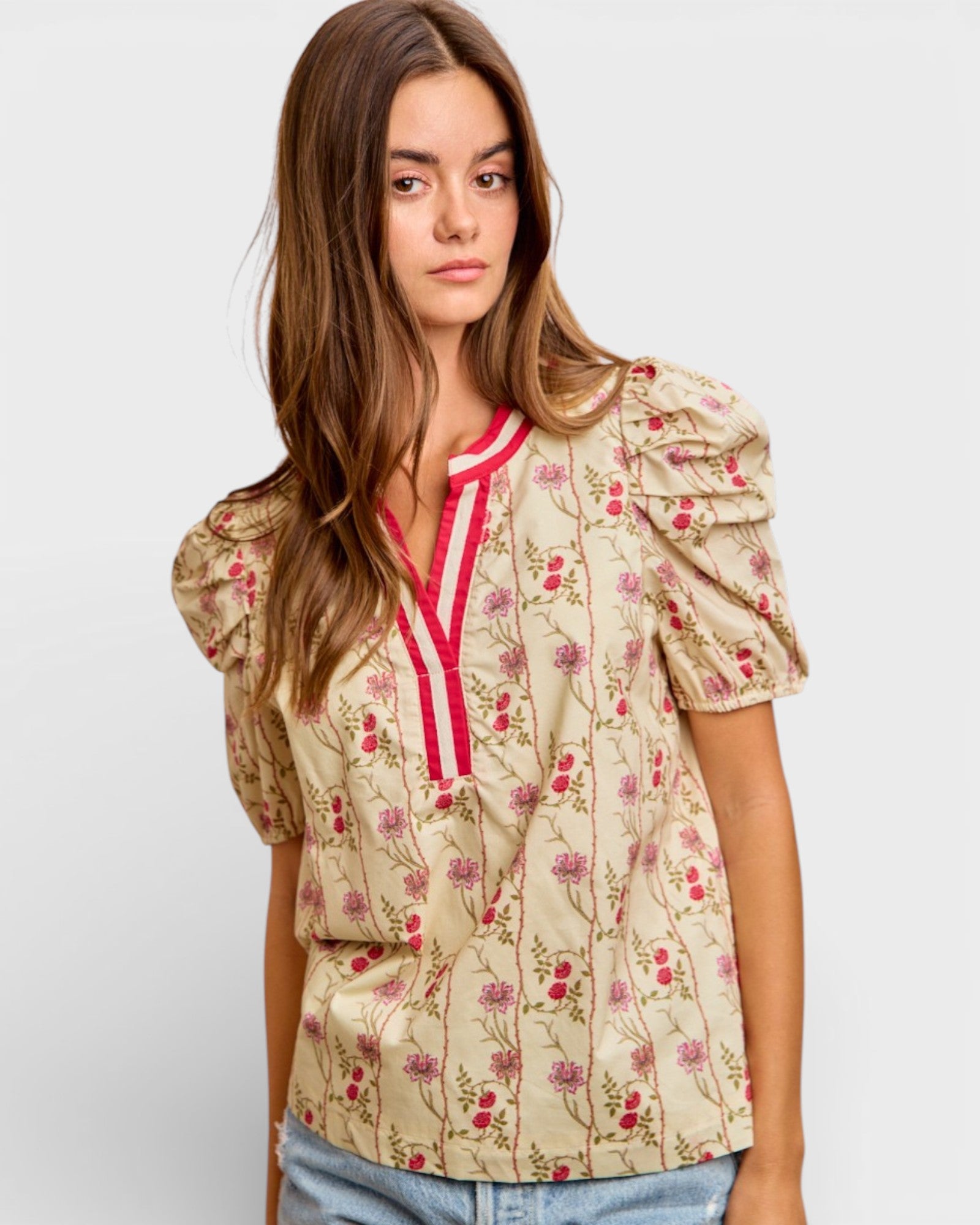 Woman wearing a floral blouse with puff sleeves on a plain background