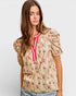 Woman wearing a floral blouse with puff sleeves on a plain background