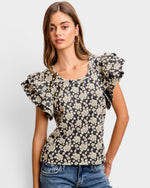 Woman wearing a floral blouse with ruffled sleeves on a plain background