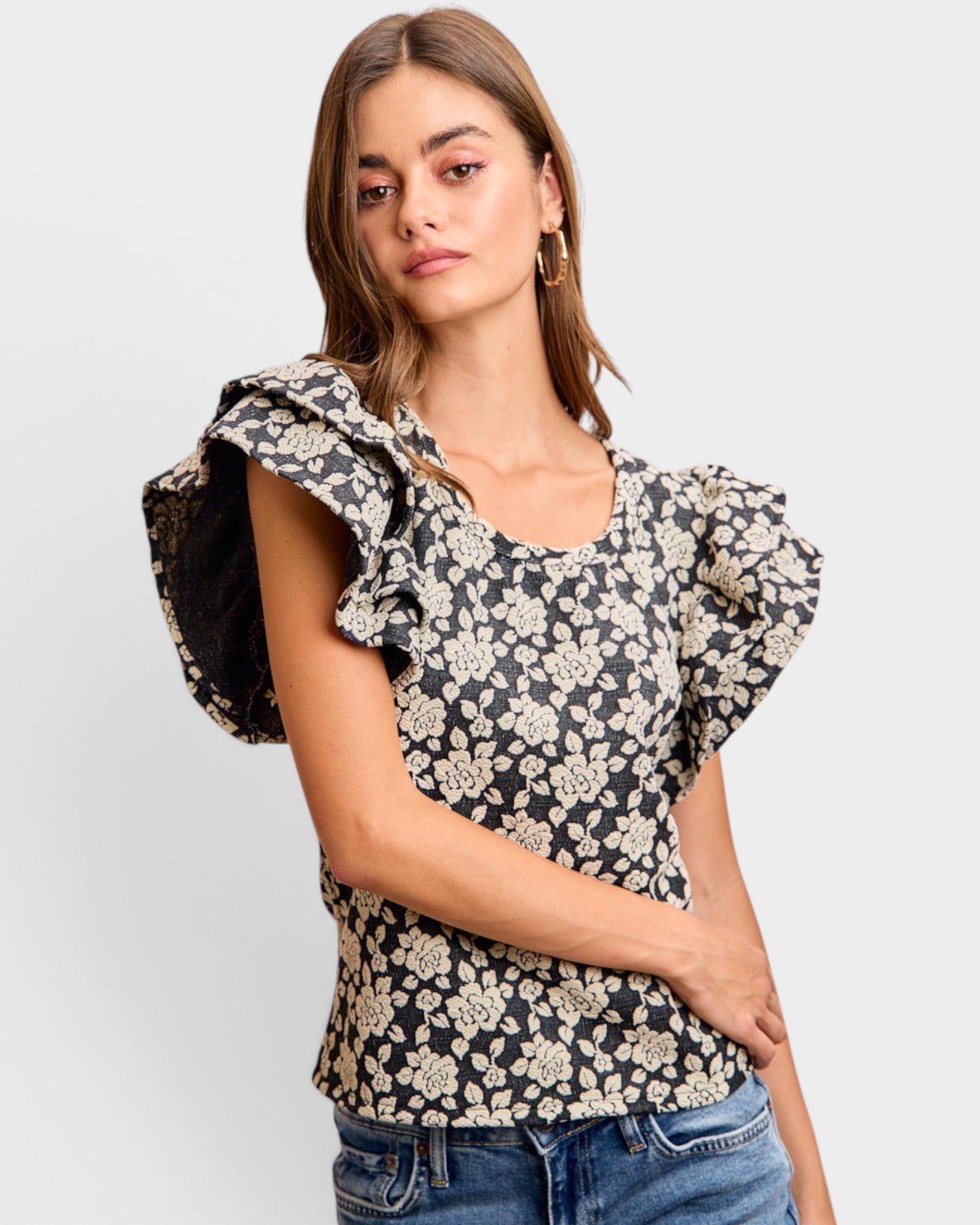 Woman wearing a floral blouse with ruffled sleeves on a plain background