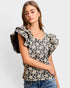 Woman wearing a floral blouse with ruffled sleeves on a plain background