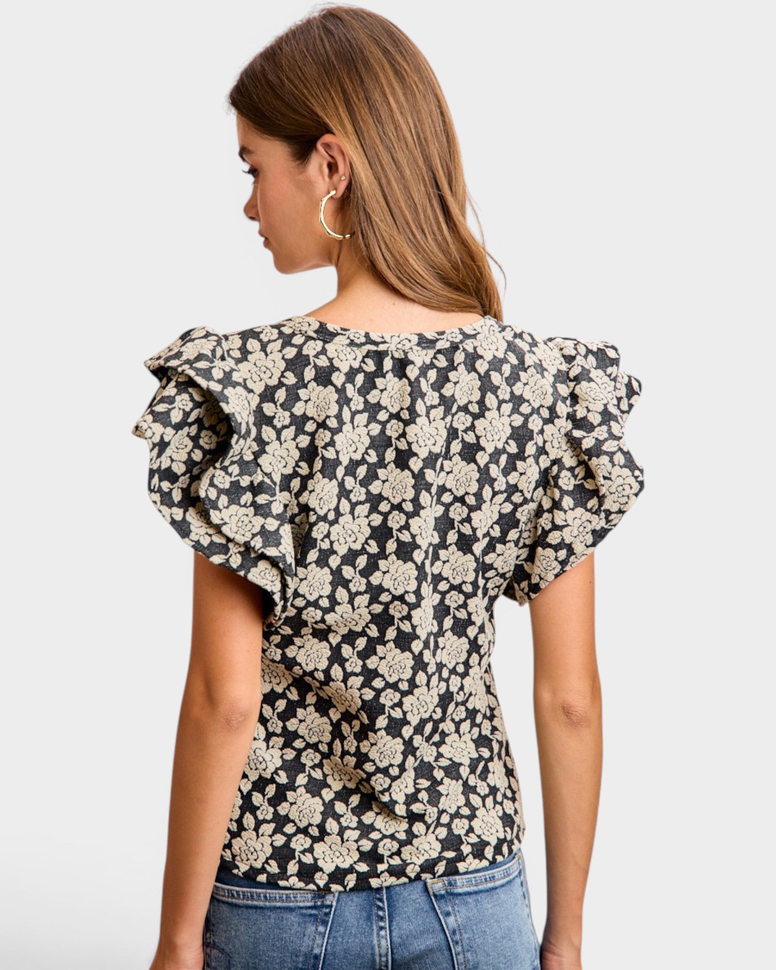 Woman wearing a floral blouse with ruffled sleeves on a white background