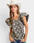 Woman wearing a floral top and white hat on a plain background