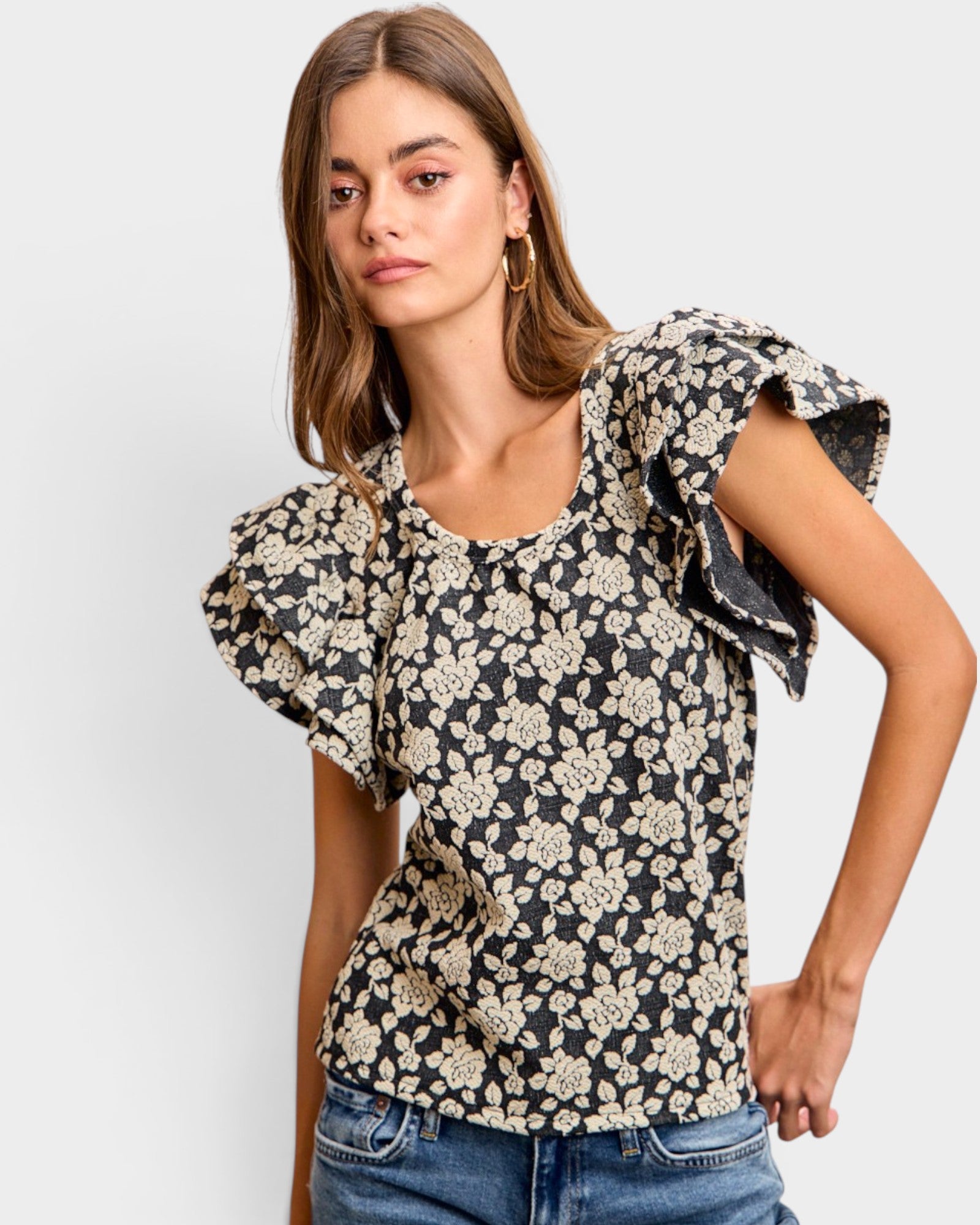 Woman wearing a floral blouse with ruffled sleeves on a plain background