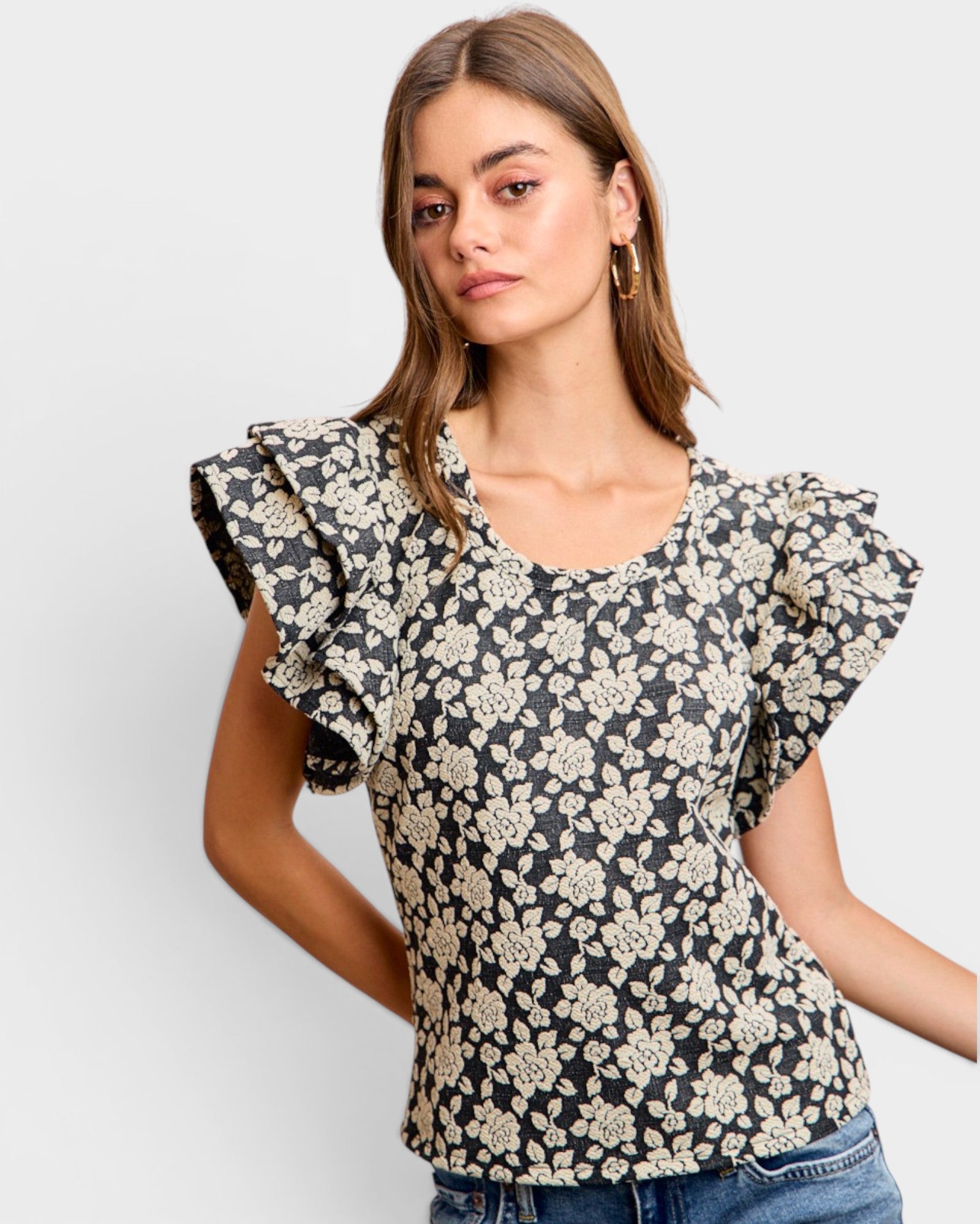 Woman wearing a floral blouse with ruffled sleeves on a white background