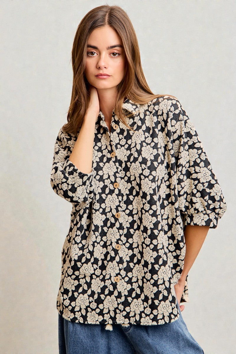 Woman wearing a black floral blouse against a plain background