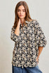 Woman wearing a black floral blouse against a plain background