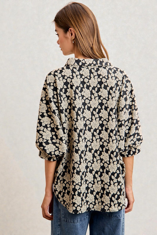 Woman wearing a black floral patterned shirt against a plain background